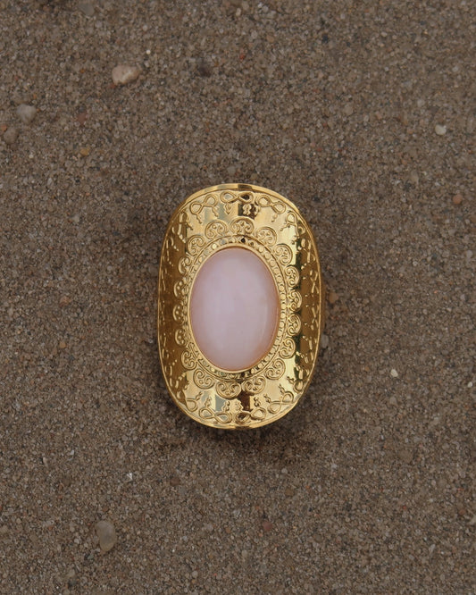 Gouden verstelbare ring met ovale vorm en grote roze steen, omringd door sierlijke details