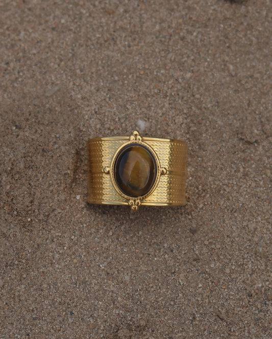Gouden verstelbare ring van stainless steel met ovale bruine steen en verfijnde details rondom de band.
