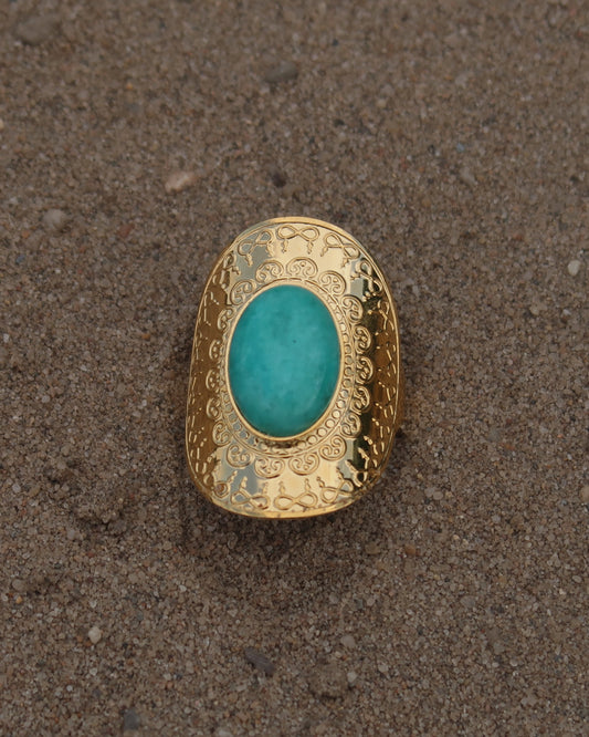 Gouden verstelbare ring met ovale vorm en grote blauwe steen, omringd door sierlijke detail.