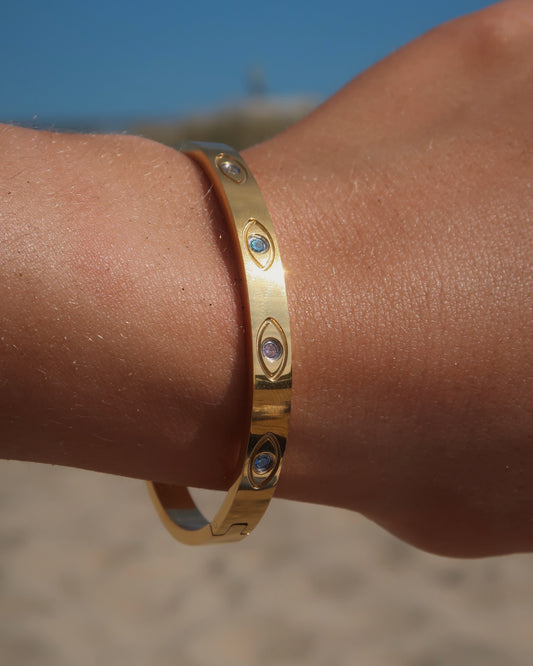 Gouden bangle met kleurrijke oogdetails en steentjes, gemaakt van stainless steel