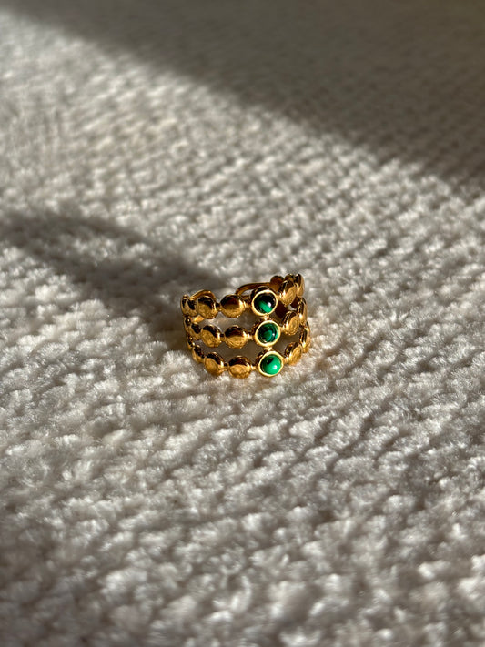 Gouden verstelbare stainless steel ring met drie groene steentjes en verfijnde details, uitgevoerd in een gelaagd design