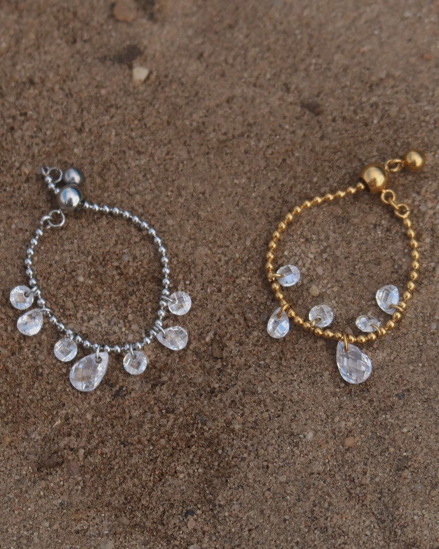 Verstelbare stainless steel ring met bolletjesbandje en hangende druppelvormige steentjes, verkrijgbaar in goud en zilver