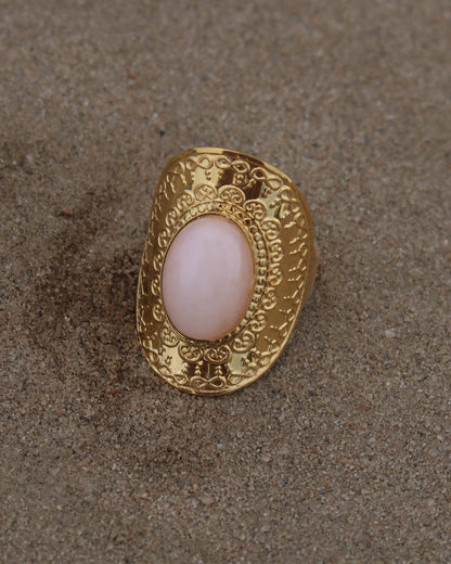 Gouden verstelbare ring met ovale vorm en grote roze steen, omringd door sierlijke details
