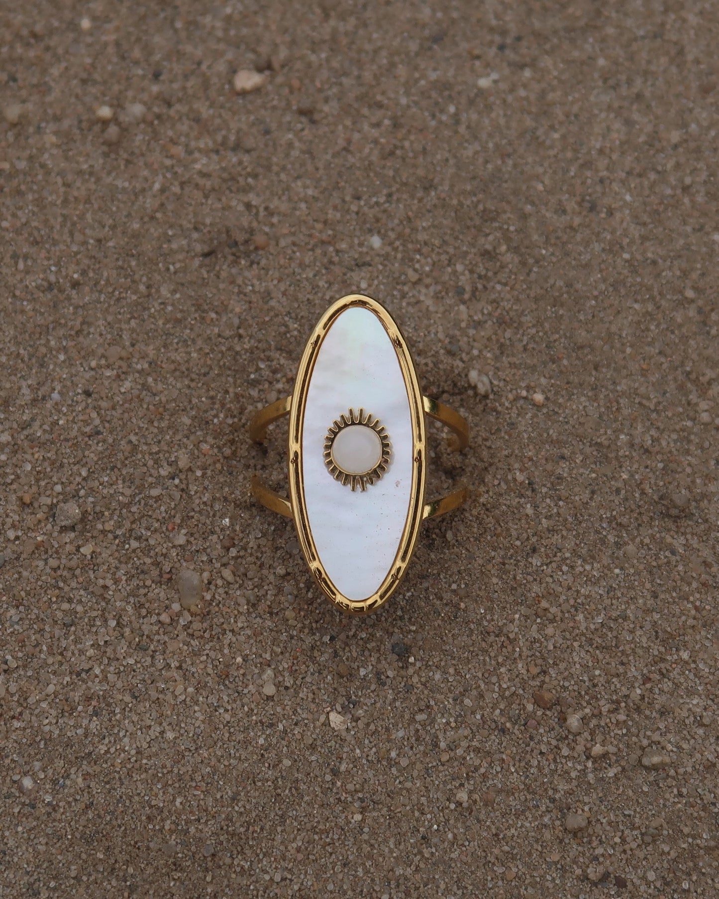 Gouden statement ring van stainless steel met ovale witte steen en parelmoerachtige afwerking, verstelbare dubbele band.