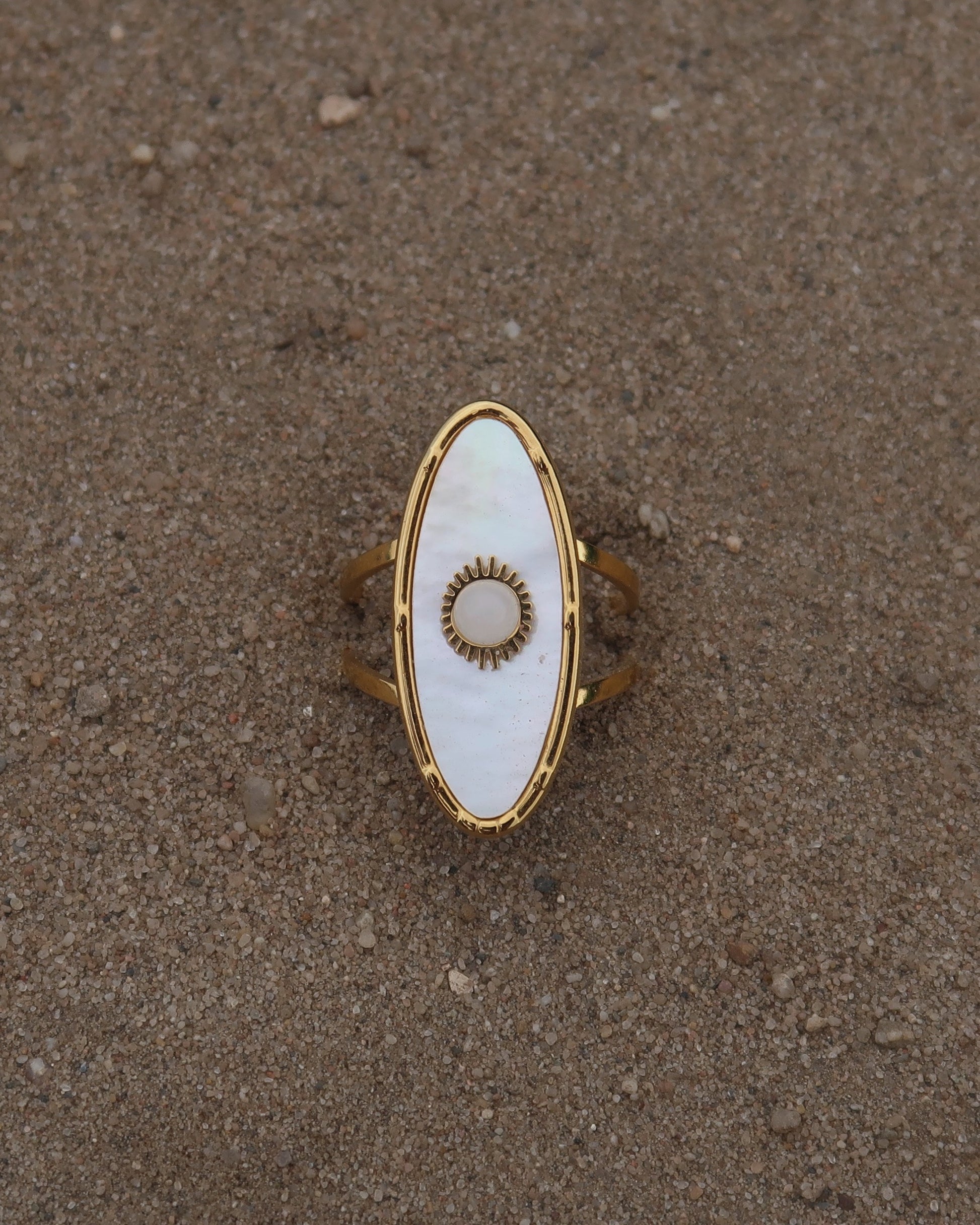 Gouden statement ring van stainless steel met ovale witte steen en parelmoerachtige afwerking, verstelbare dubbele band.