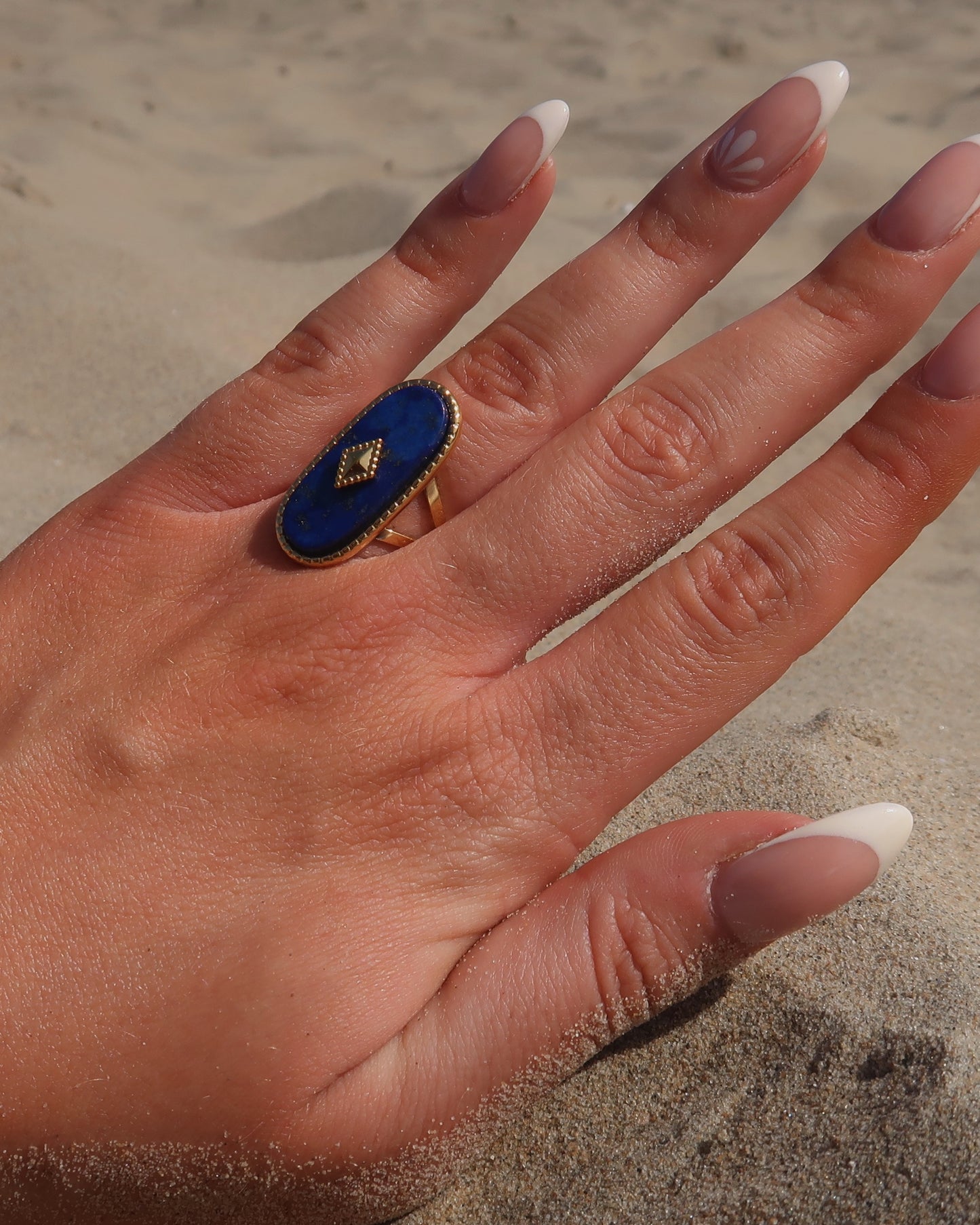 Gouden stainless steel verstelbare ring met een grote donkerblauwe ovale steen, een gouden ruit in het midden en verfijnde details rondom
