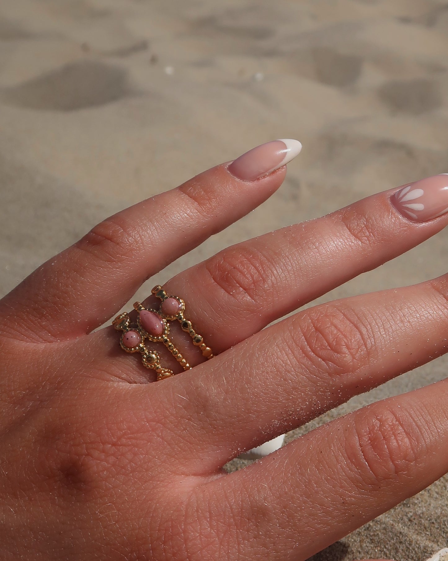 Gouden verstelbare stainless steel ring met drie roze steentjes en verfijnde details, uitgevoerd in een gelaagd design