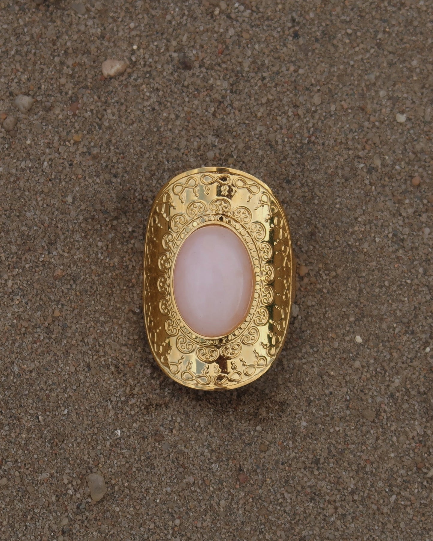 Gouden verstelbare ring met ovale vorm en grote roze steen, omringd door sierlijke details