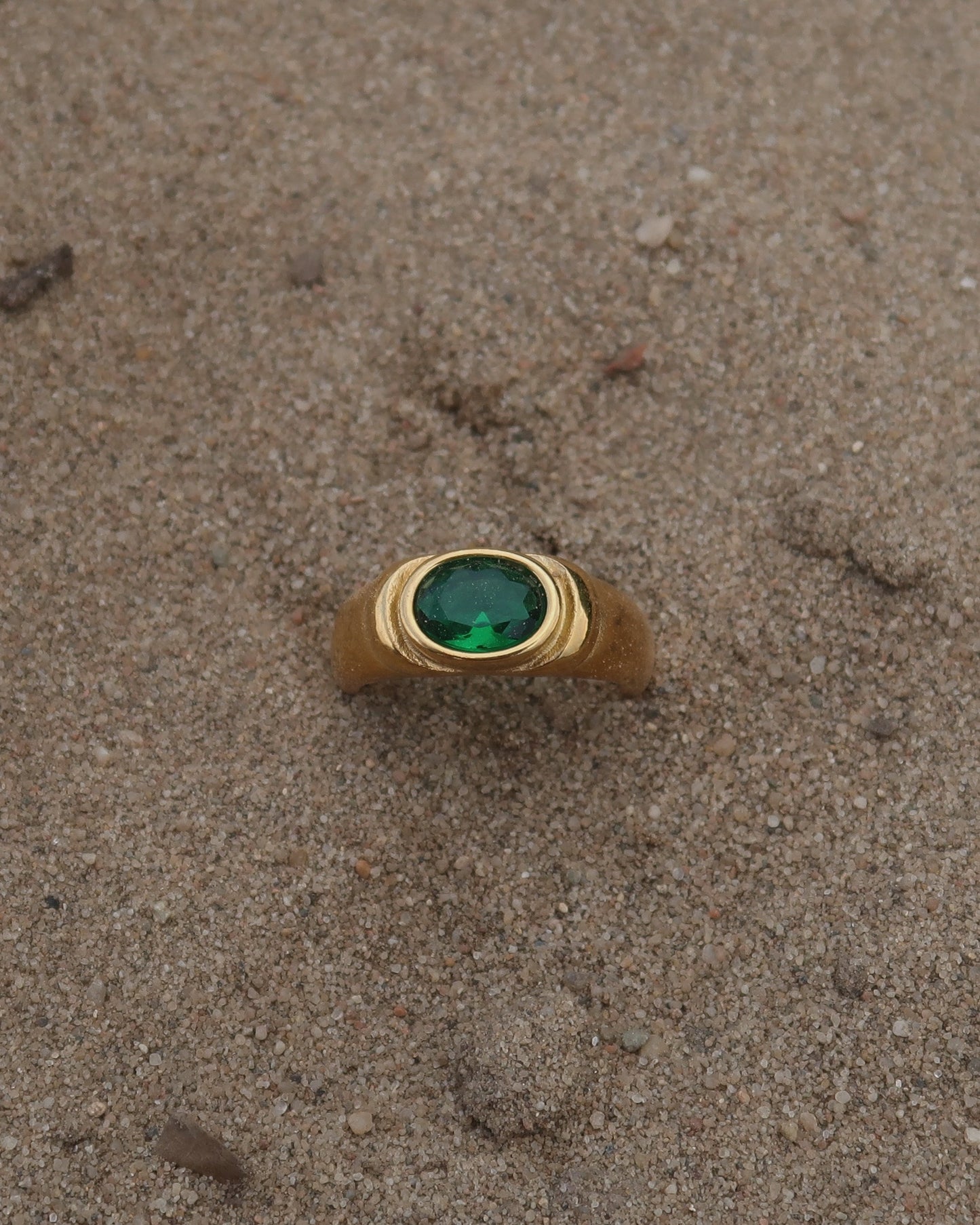 Gouden ring van stainless steel met een gladde band en een opvallende groene steen in het midden