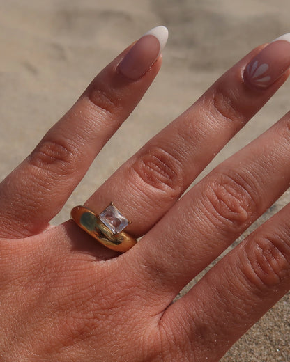 Gouden ring met glad design en een zilverkleurige steen aan de bovenzijde, gemaakt van waterproof stainless steel.