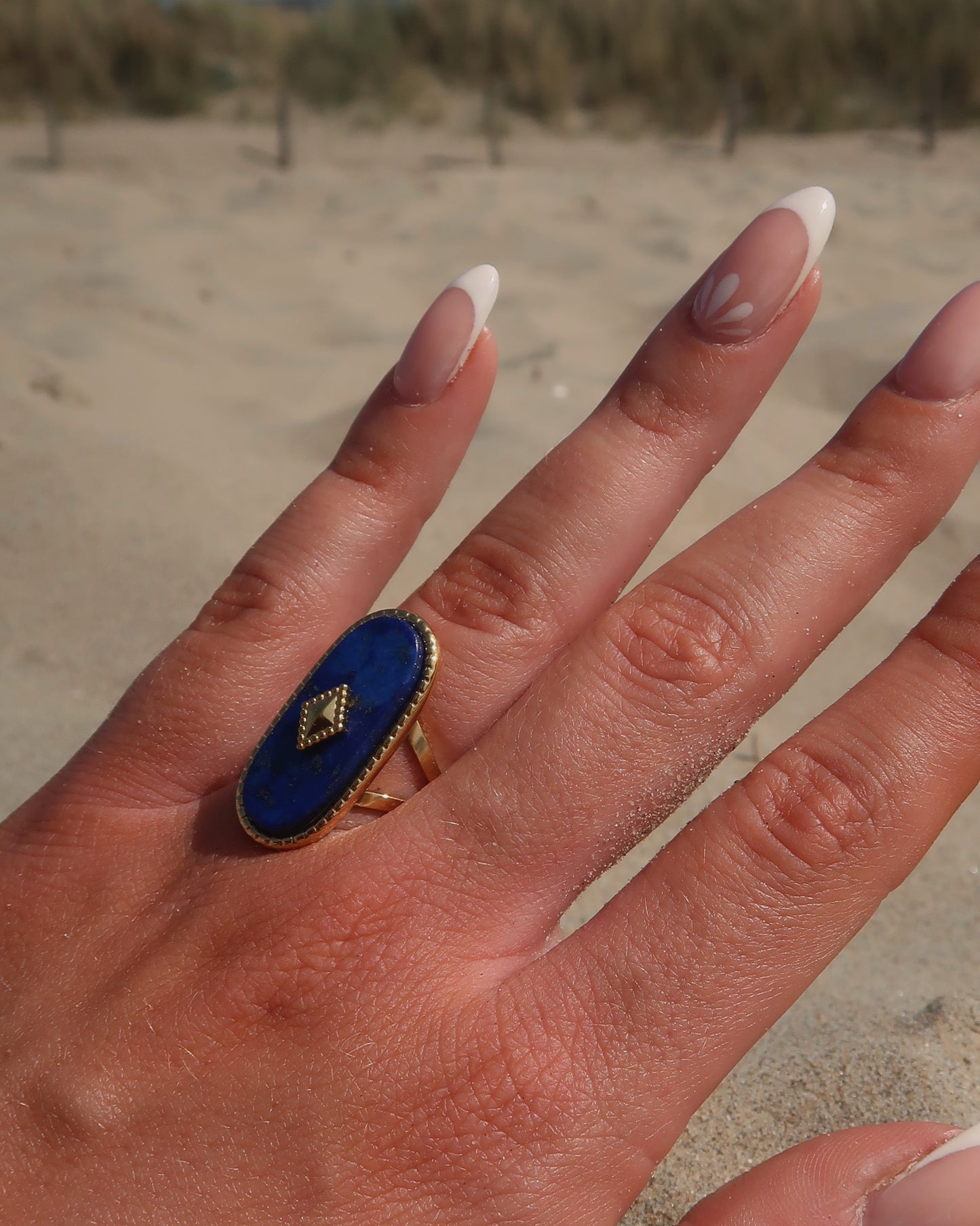 Gouden stainless steel verstelbare ring met een grote donkerblauwe ovale steen, een gouden ruit in het midden en verfijnde details rondom
