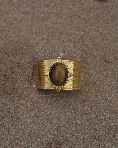 Gouden verstelbare ring van stainless steel met ovale bruine steen en verfijnde details rondom de band.