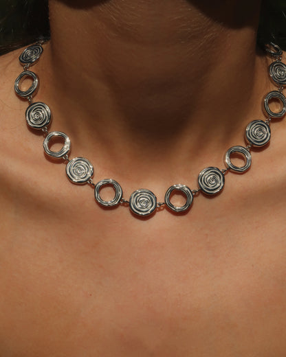 Zilveren statementketting met aaneengeschakelde ronde schelpvormen in verschillende stijlen.