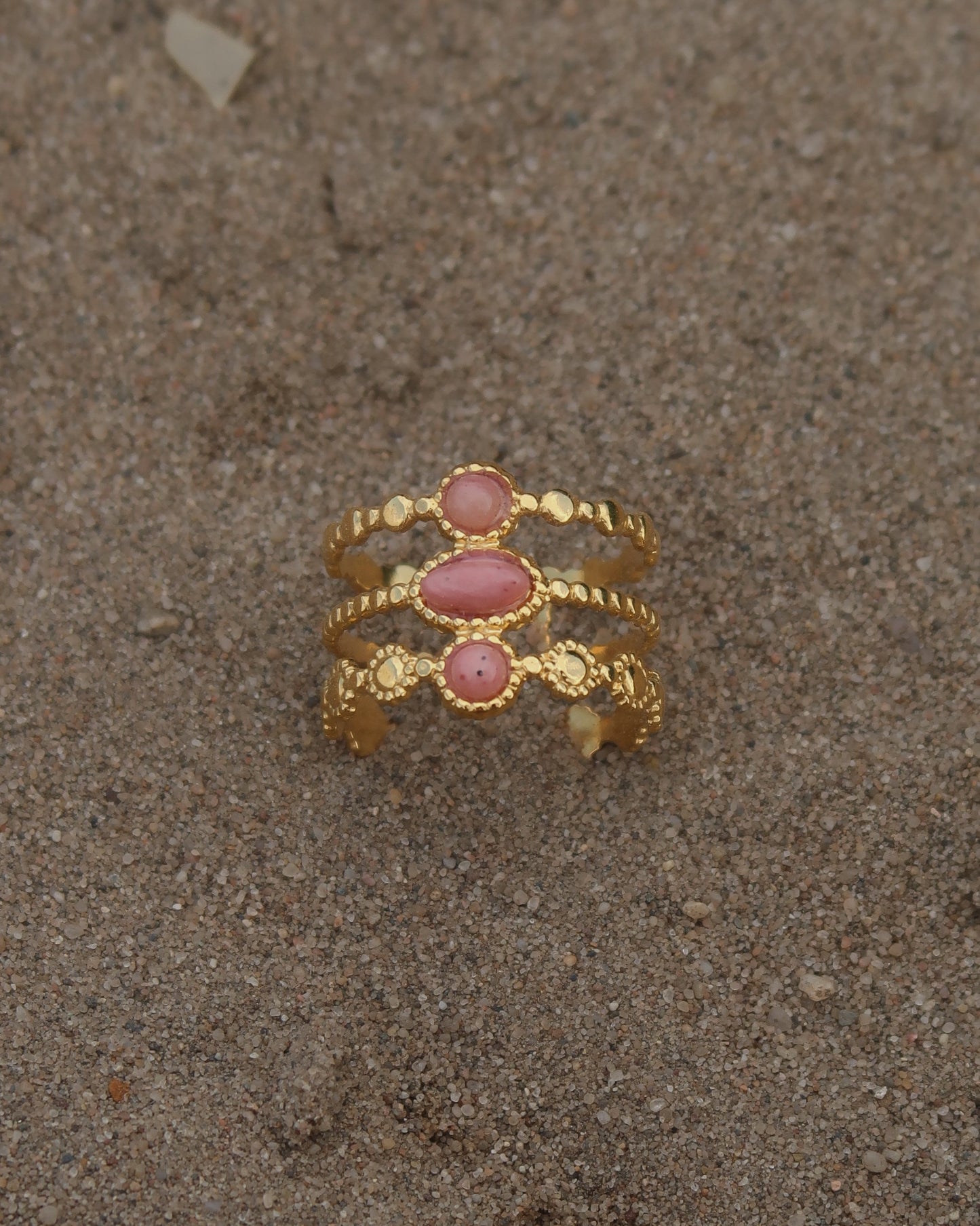 Gouden verstelbare stainless steel ring met drie roze steentjes en verfijnde details, uitgevoerd in een gelaagd design