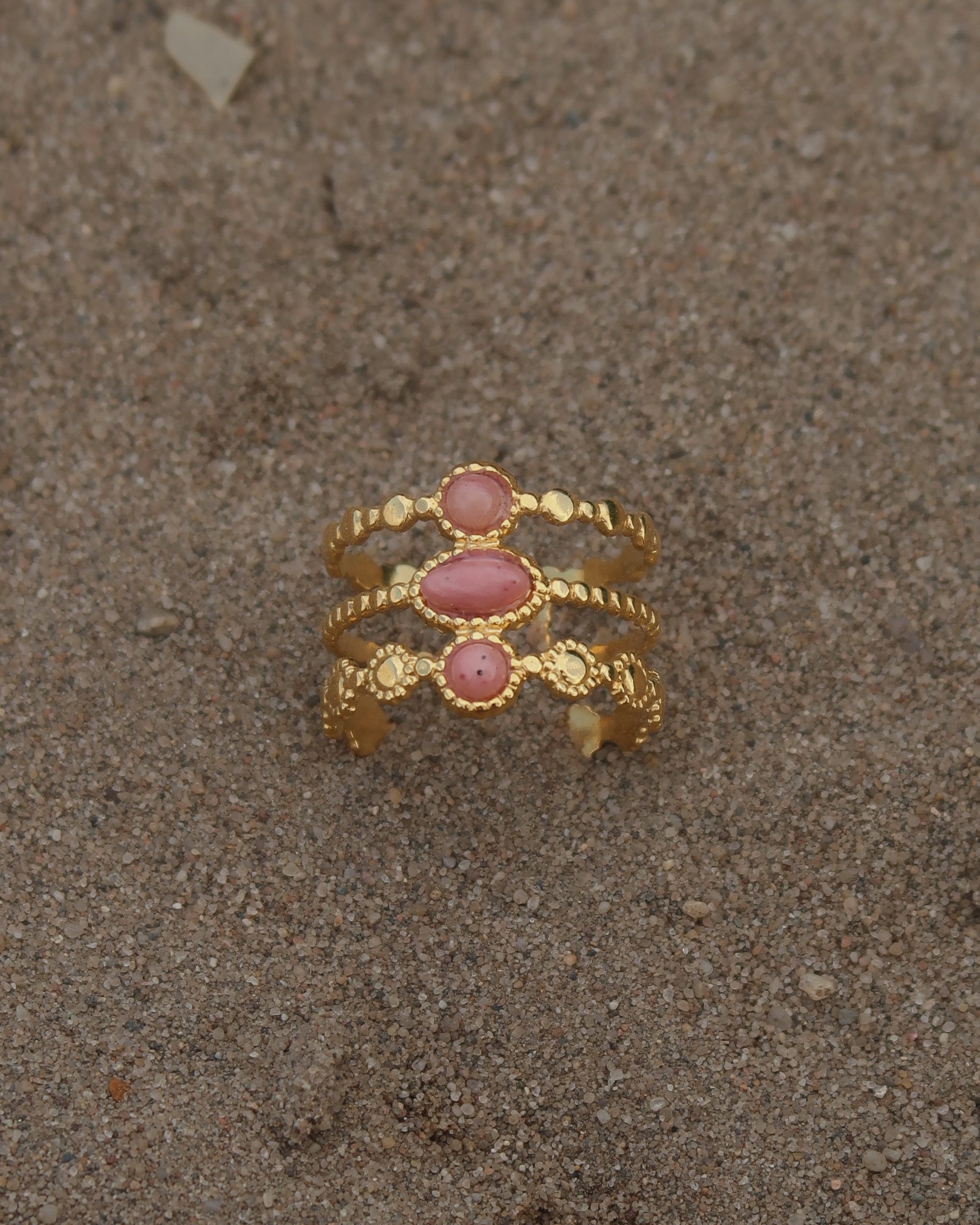 Gouden verstelbare stainless steel ring met drie roze steentjes en verfijnde details, uitgevoerd in een gelaagd design
