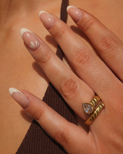 Gouden spiraalvormige ring met reliëf en zilverkleurige druppelvormige steen aan het uiteinde, gemaakt van stainless steel