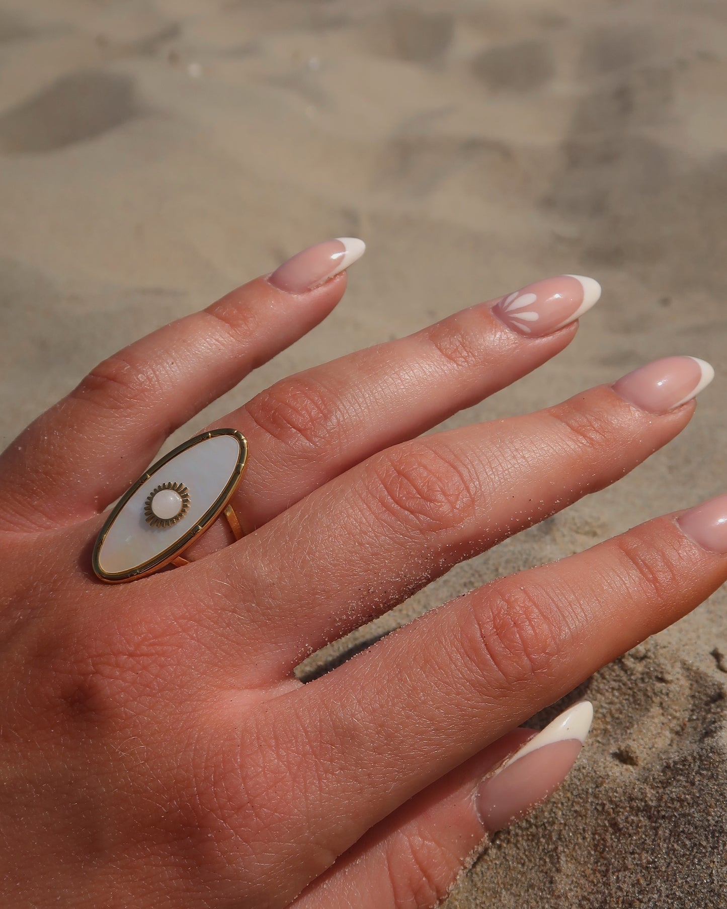 Gouden statement ring van stainless steel met ovale witte steen en parelmoerachtige afwerking, verstelbare dubbele band.