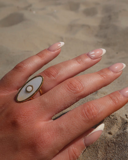 Gouden statement ring van stainless steel met ovale witte steen en parelmoerachtige afwerking, verstelbare dubbele band.
