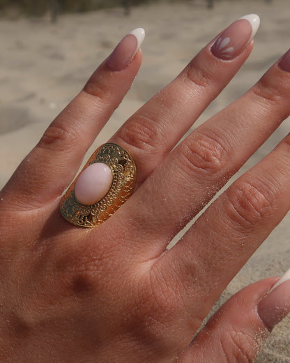 Gouden verstelbare ring met ovale vorm en grote roze steen, omringd door sierlijke details