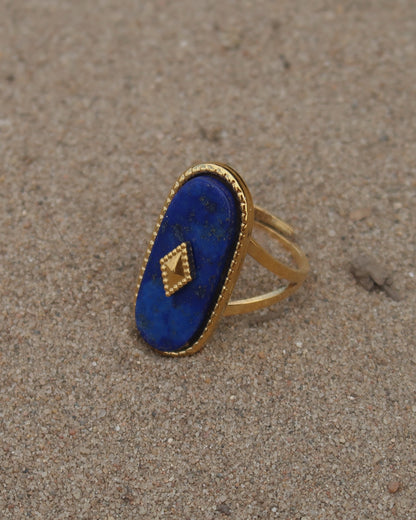 Gouden stainless steel verstelbare ring met een grote donkerblauwe ovale steen, een gouden ruit in het midden en verfijnde details rondom
