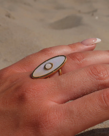 Gouden statement ring van stainless steel met ovale witte steen en parelmoerachtige afwerking, verstelbare dubbele band.