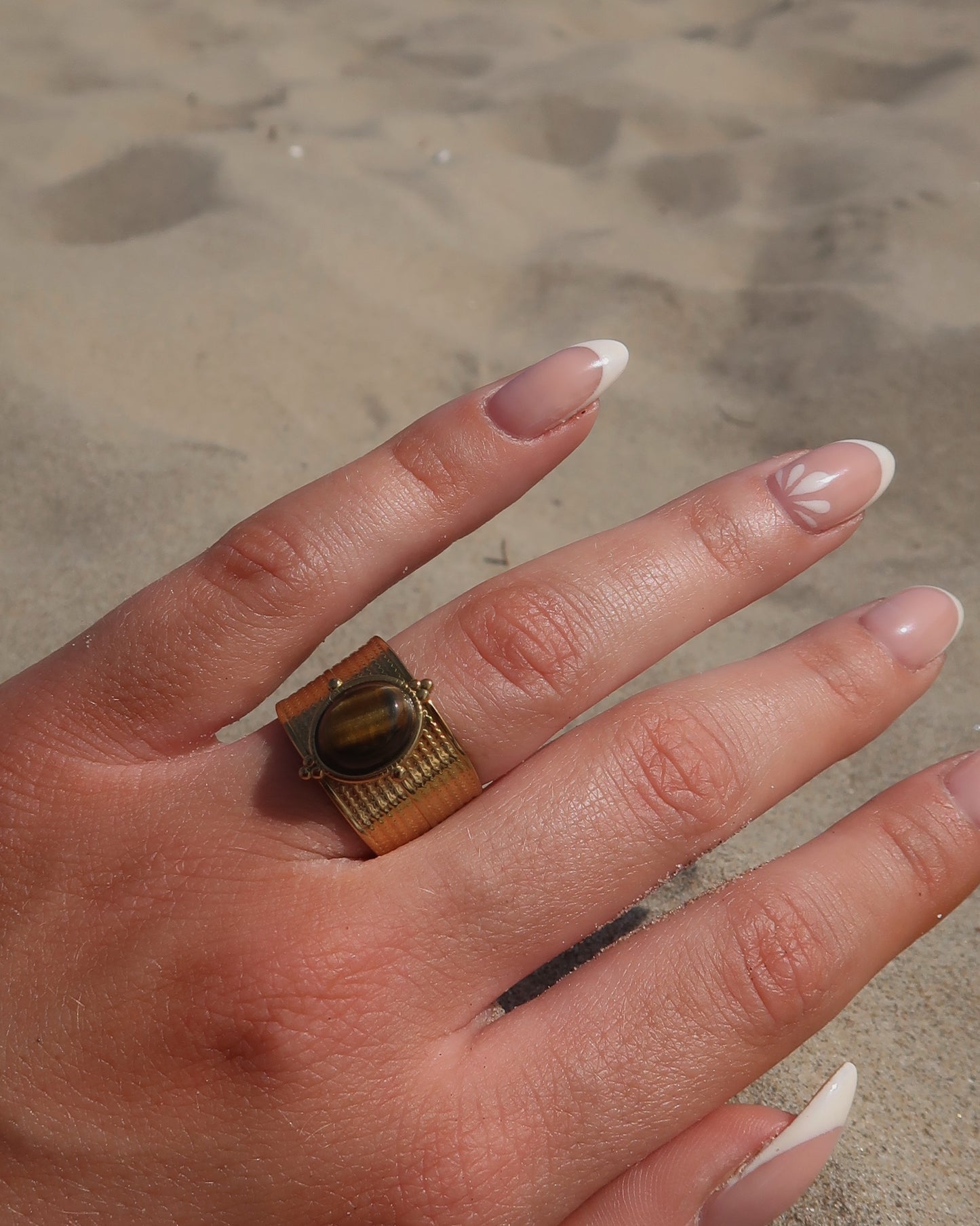 Gouden verstelbare ring van stainless steel met ovale bruine steen en verfijnde details rondom de band.