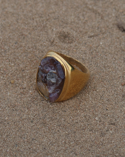 Grote gouden ring van stainless steel met een gladde band en een rechthoekig vlak gevuld met lichtpaarse amethist-achtige steentjes