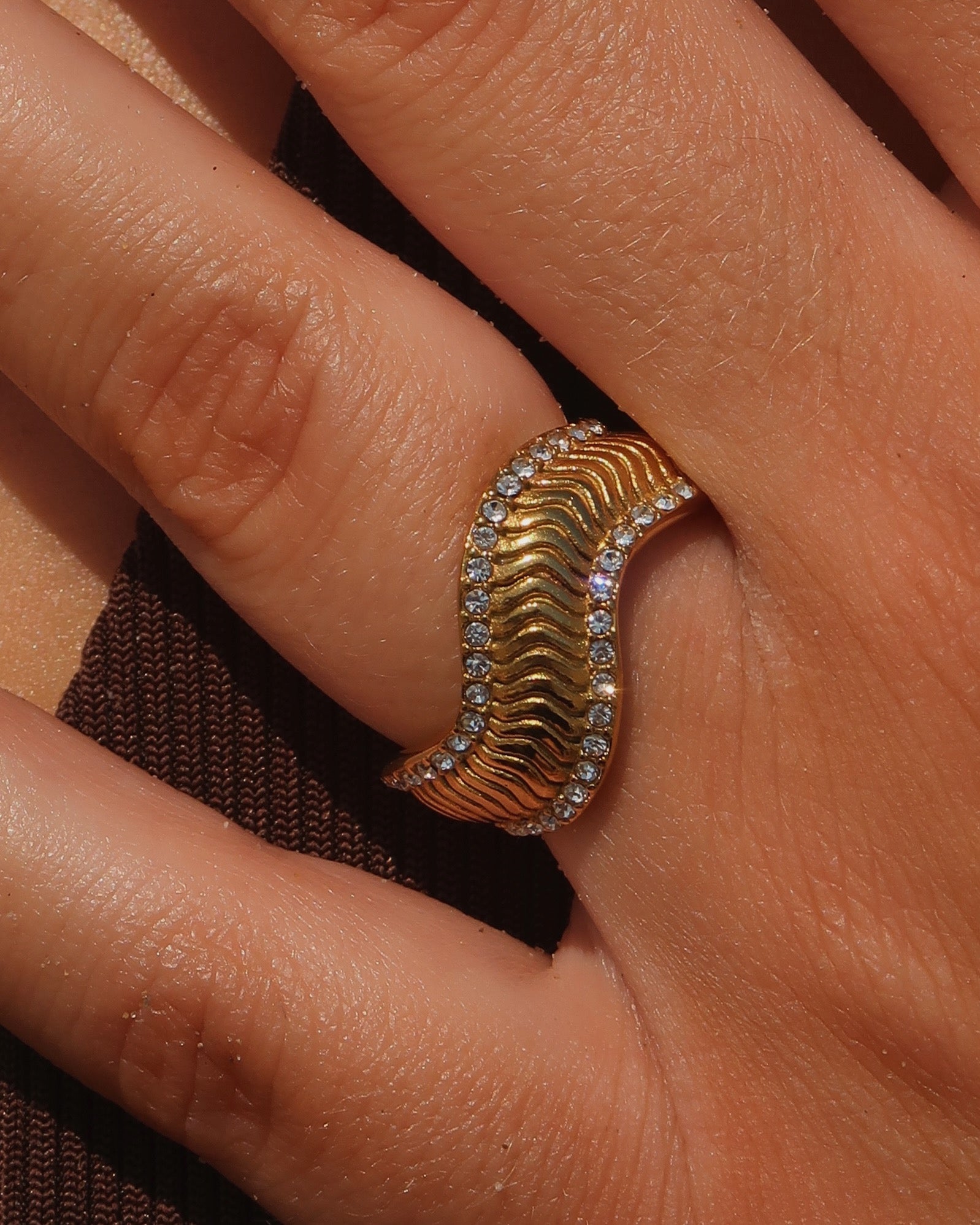 Gouden ring met golvend reliëf en zilverkleurige steentjes langs de randen - gemaakt van stainless steel
