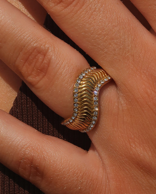 Gouden ring met golvend reliëf en zilverkleurige steentjes langs de randen - gemaakt van stainless steel
