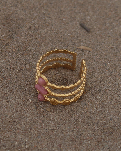 Gouden verstelbare stainless steel ring met drie roze steentjes en verfijnde details, uitgevoerd in een gelaagd design