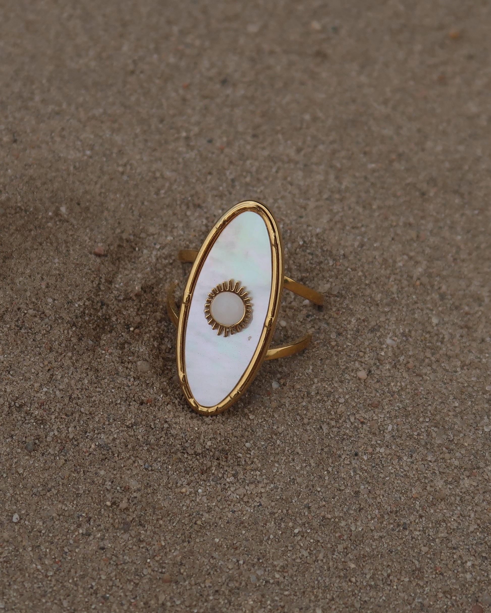 Gouden statement ring van stainless steel met ovale witte steen en parelmoerachtige afwerking, verstelbare dubbele band.