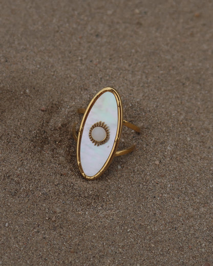 Gouden statement ring van stainless steel met ovale witte steen en parelmoerachtige afwerking, verstelbare dubbele band.