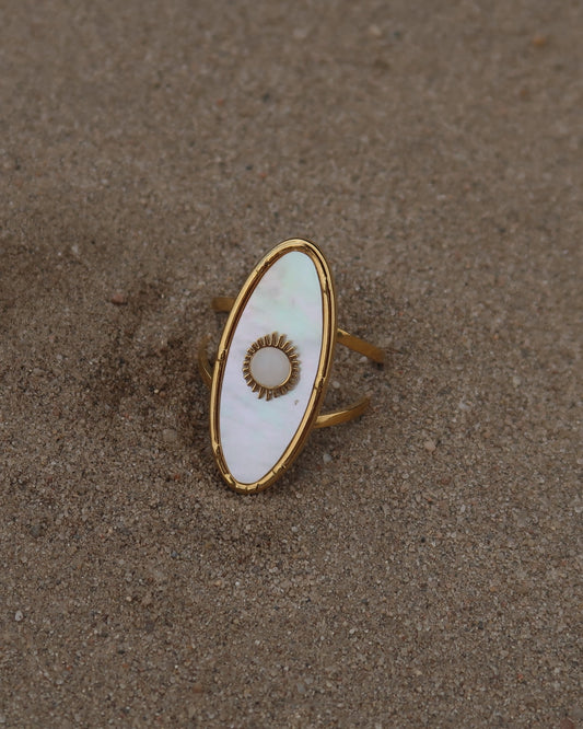 Gouden statement ring van stainless steel met ovale witte steen en parelmoerachtige afwerking, verstelbare dubbele band.