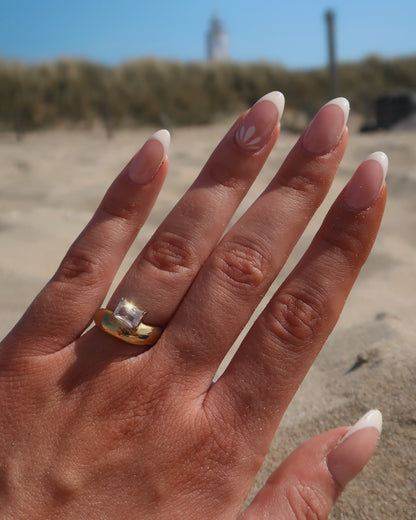 Gouden ring met glad design en een zilverkleurige steen aan de bovenzijde, gemaakt van waterproof stainless steel.