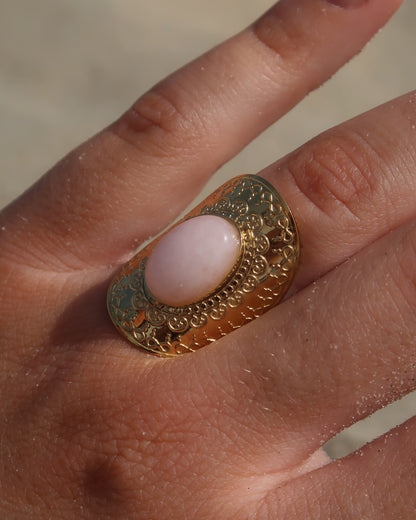 Gouden verstelbare ring met ovale vorm en grote roze steen, omringd door sierlijke details