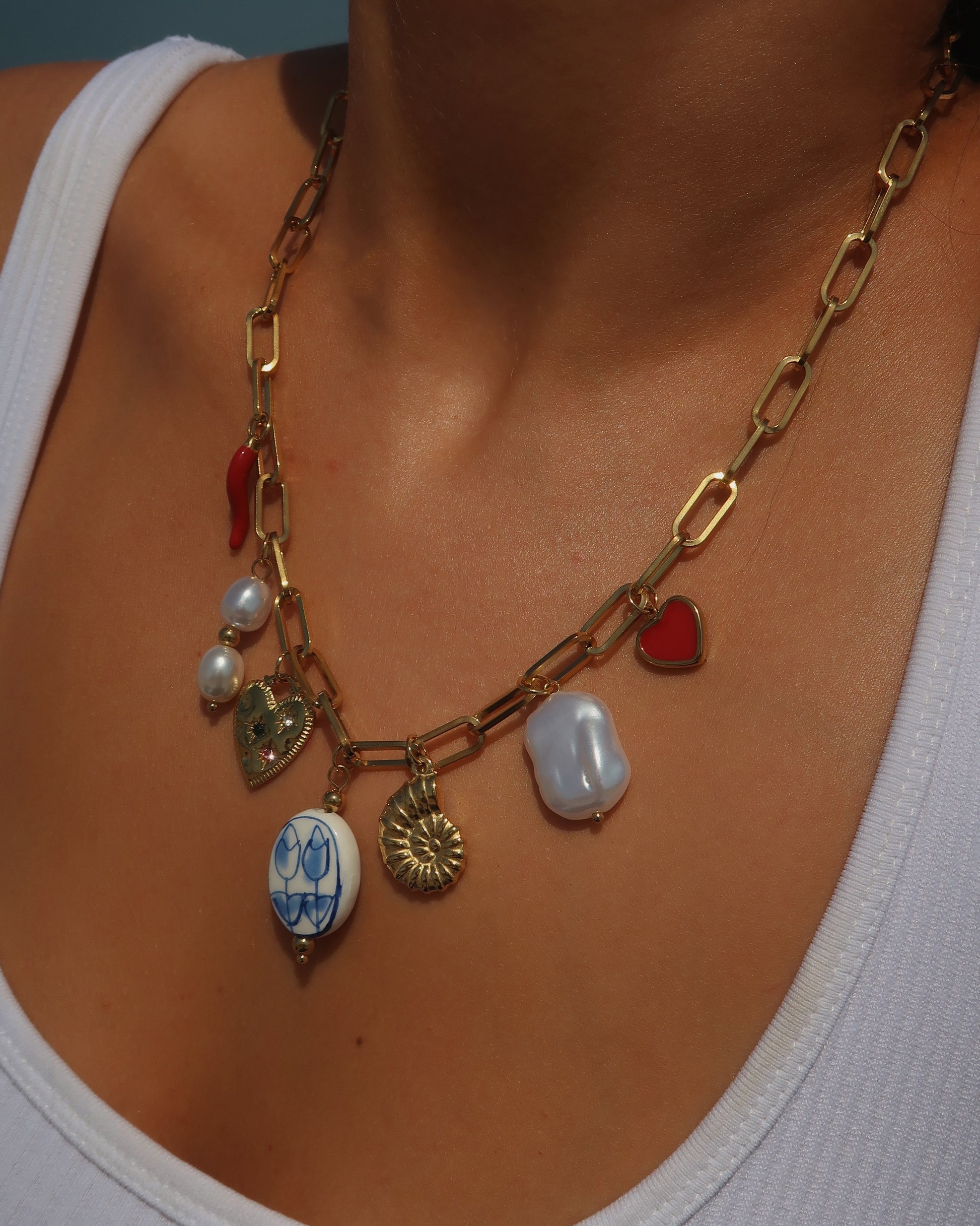 Gouden ketting met zeven bedels, waaronder een chilipeper, hartje en schelp – kleurrijk en speels ontwerp