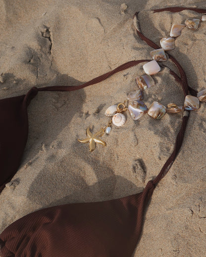 Statement ketting met goudkleurige schelpen en afneembare hangers, waaronder een zeester en schelpen met een bruine bikini