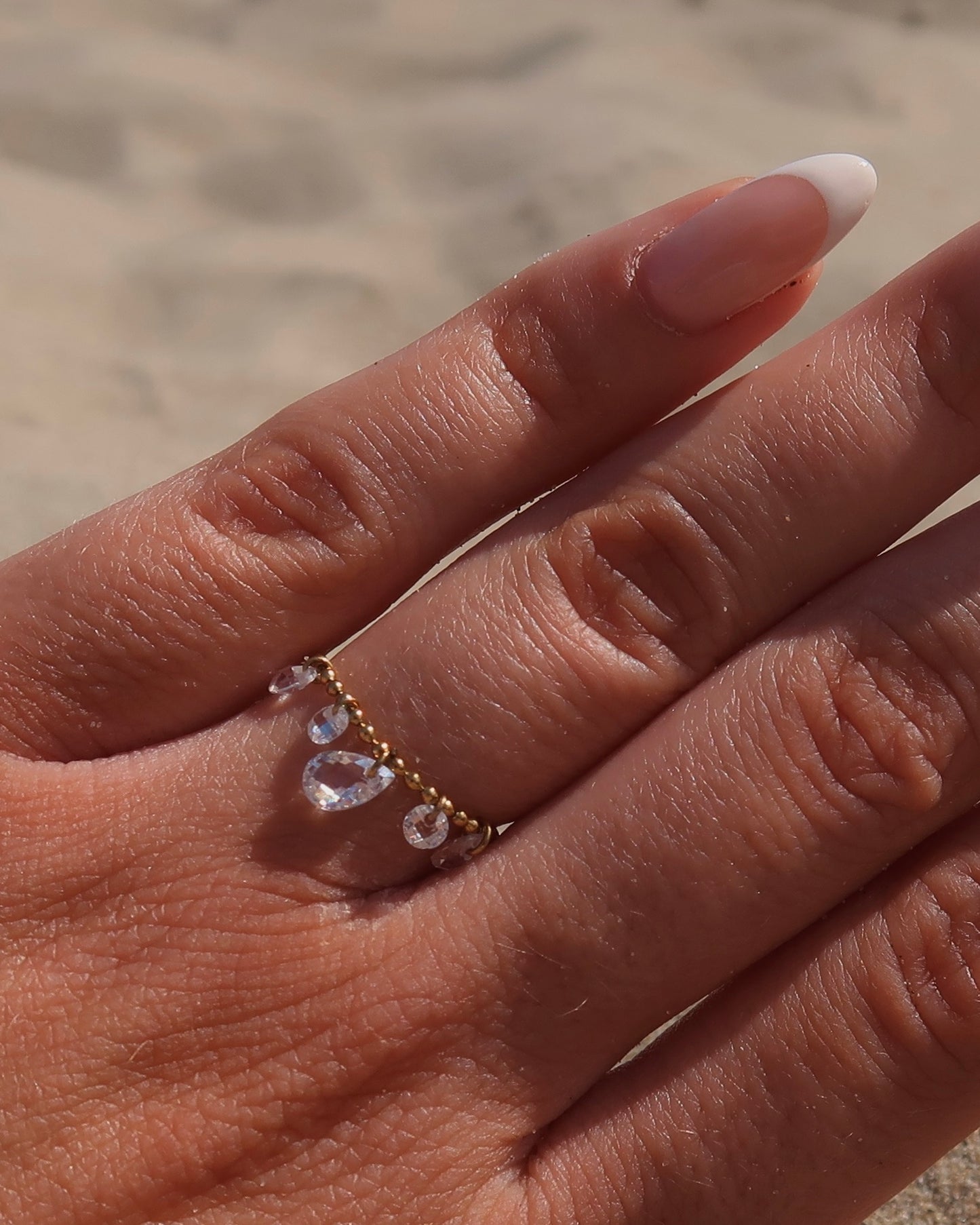 Verstelbare stainless steel ring met bolletjesbandje en hangende druppelvormige steentjes, verkrijgbaar in goud en zilver