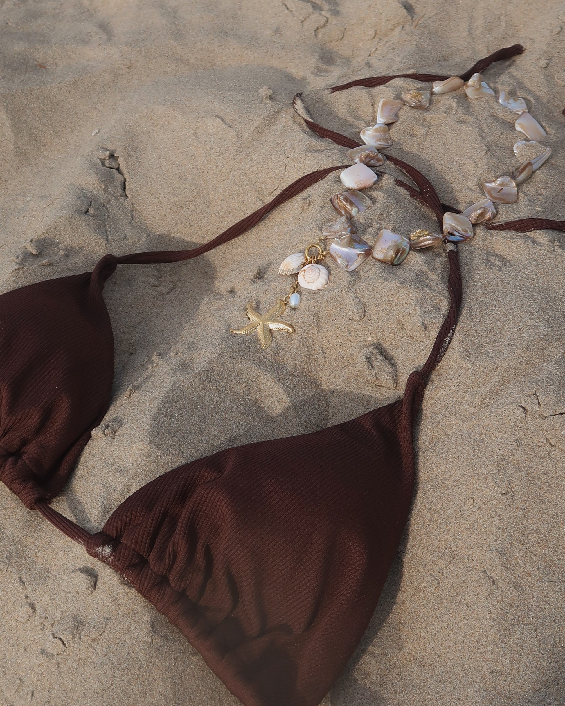 Statement ketting met goudkleurige schelpen en afneembare hangers, waaronder een zeester en schelpen met een bruine bikini