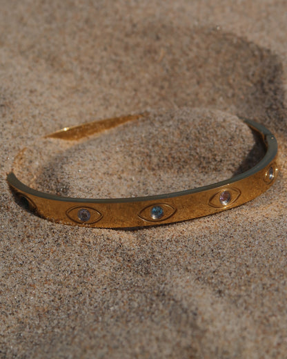 Gouden bangle met kleurrijke oogdetails en steentjes, gemaakt van stainless steel