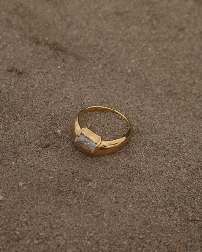 Gouden ring met glad design en een zilverkleurige steen aan de bovenzijde, gemaakt van waterproof stainless steel.