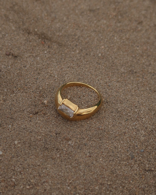 Gouden ring met glad design en een zilverkleurige steen aan de bovenzijde, gemaakt van waterproof stainless steel.