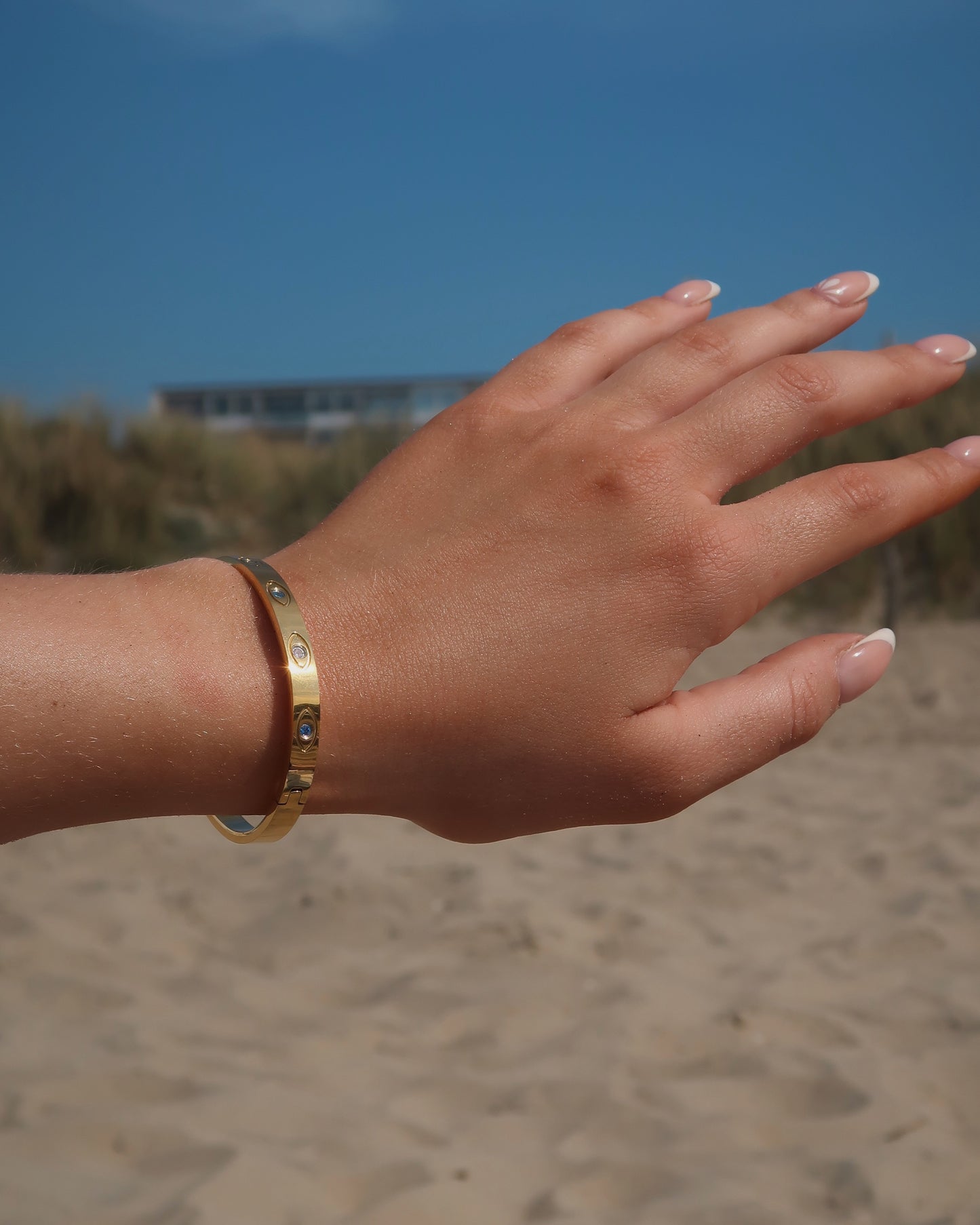 Gouden bangle met kleurrijke oogdetails en steentjes, gemaakt van stainless steel