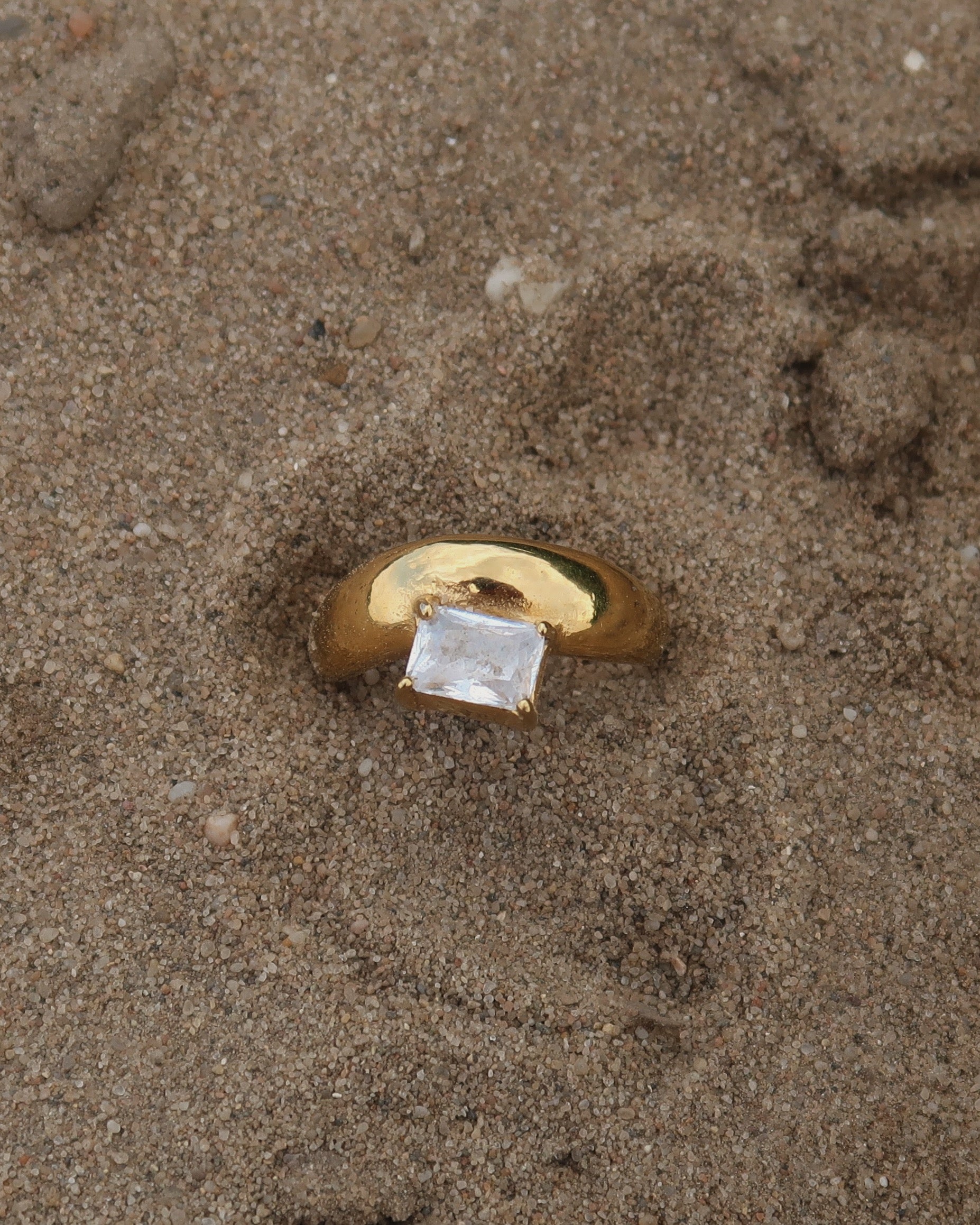 Gouden ring met glad design en een zilverkleurige steen aan de bovenzijde, gemaakt van waterproof stainless steel.