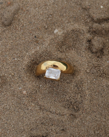 Gouden ring met glad design en een zilverkleurige steen aan de bovenzijde, gemaakt van waterproof stainless steel.