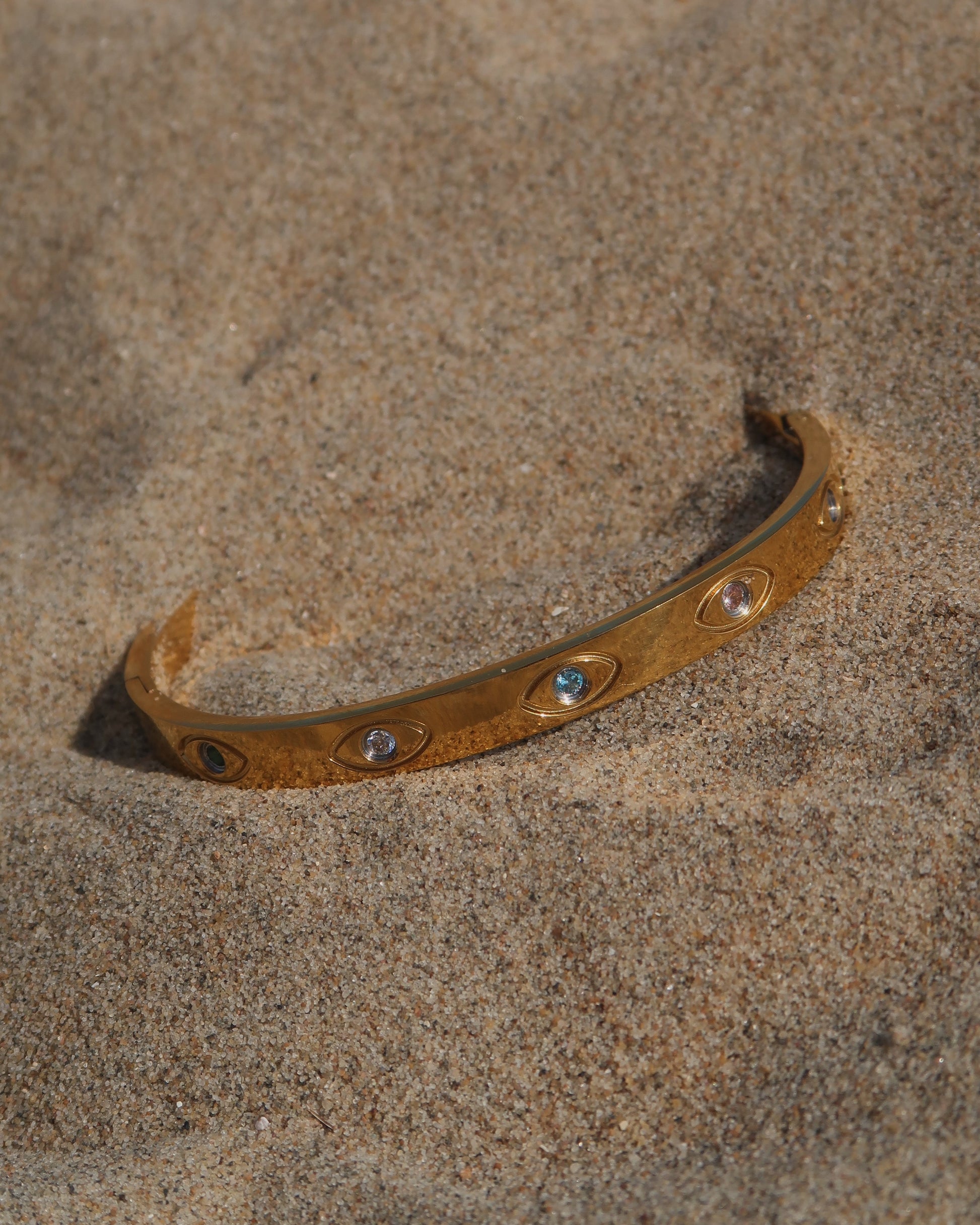 Gouden bangle met kleurrijke oogdetails en steentjes, gemaakt van stainless steel