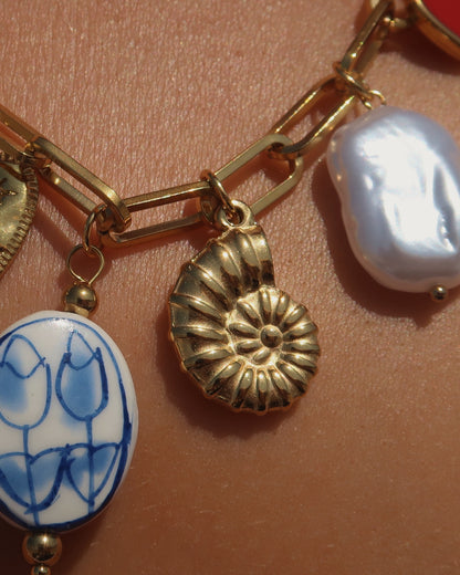 Gouden ketting met zeven bedels, waaronder een chilipeper, hartje en schelp – kleurrijk en speels ontwerp