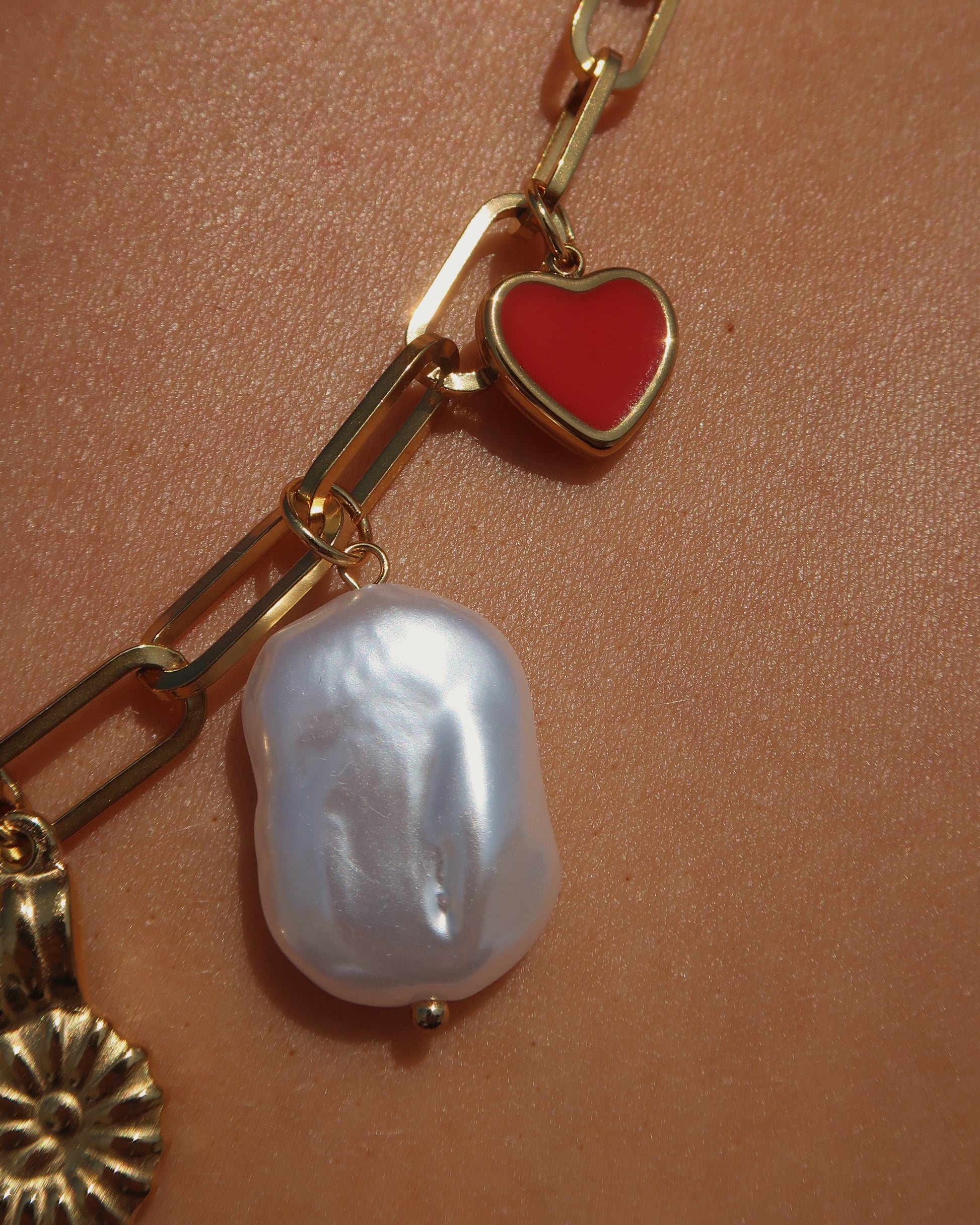 Gouden ketting met zeven bedels, waaronder een chilipeper, hartje en schelp – kleurrijk en speels ontwerp