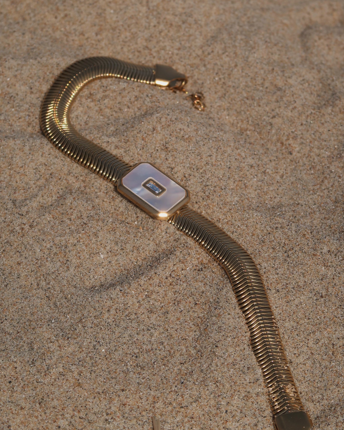 Dolly Bracelet met verfijnd slangenbandje, witte glanzende steen en verstelbare sluiting; waterproof en gemaakt van stainless steel.