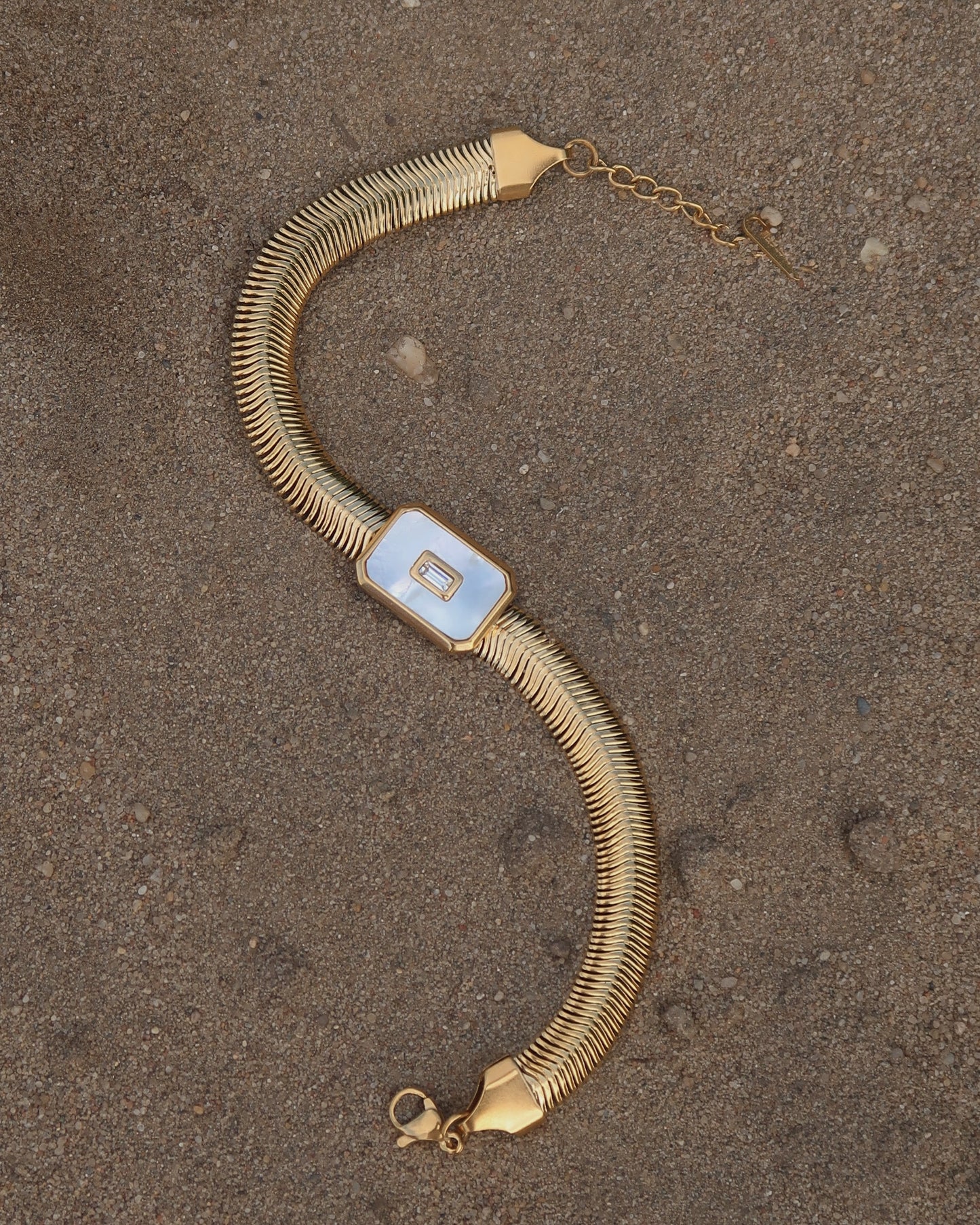 Dolly Bracelet met verfijnd slangenbandje, witte glanzende steen en verstelbare sluiting; waterproof en gemaakt van stainless steel.